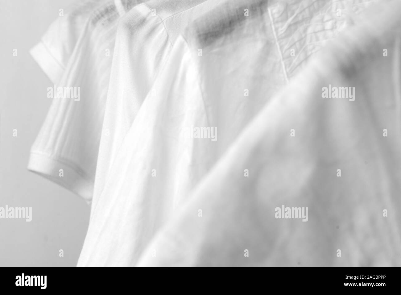 Ligne de vêtements en coton blanc accrocher sur des cintres noir sur la grille d'un magasin. Femme armoire minimaliste. Close-up. Banque D'Images