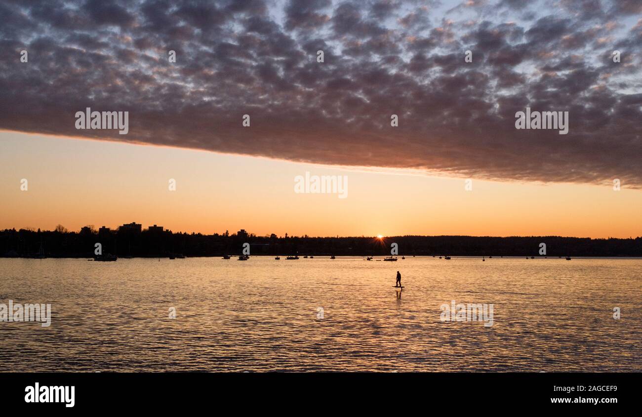 Un surfeur fait une hydroglisseur électrique à travers la baie English, sous un ciel spectaculaire au coucher du soleil à Vancouver, en Colombie-Britannique, au Canada Banque D'Images