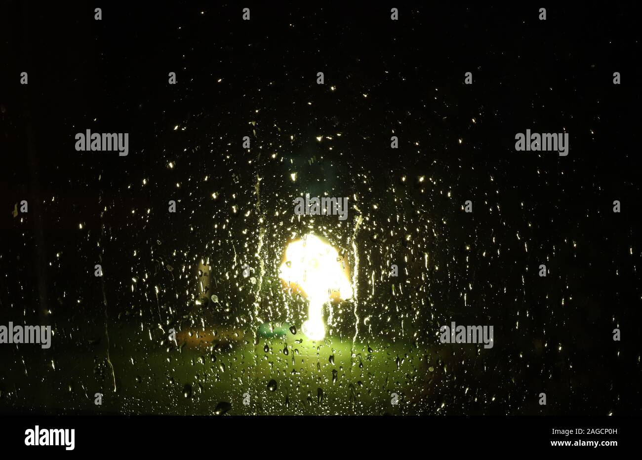 L'eau de pluie sur les vitres avec la lumière se reflétant dans les milieux. Banque D'Images