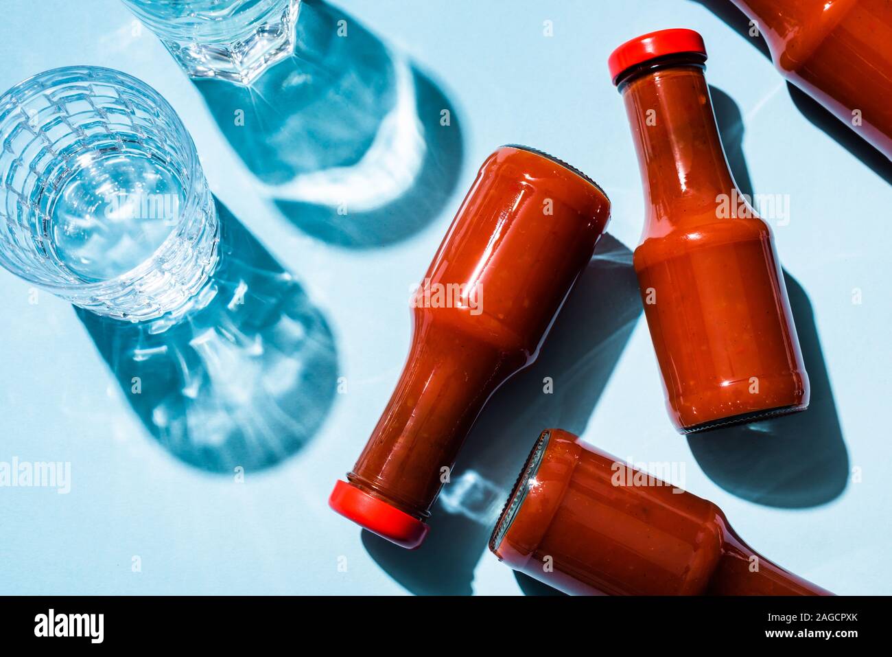 Vue de dessus de deux verres d'eau avec de la sauce tomate dans des bouteilles sur fond bleu Banque D'Images