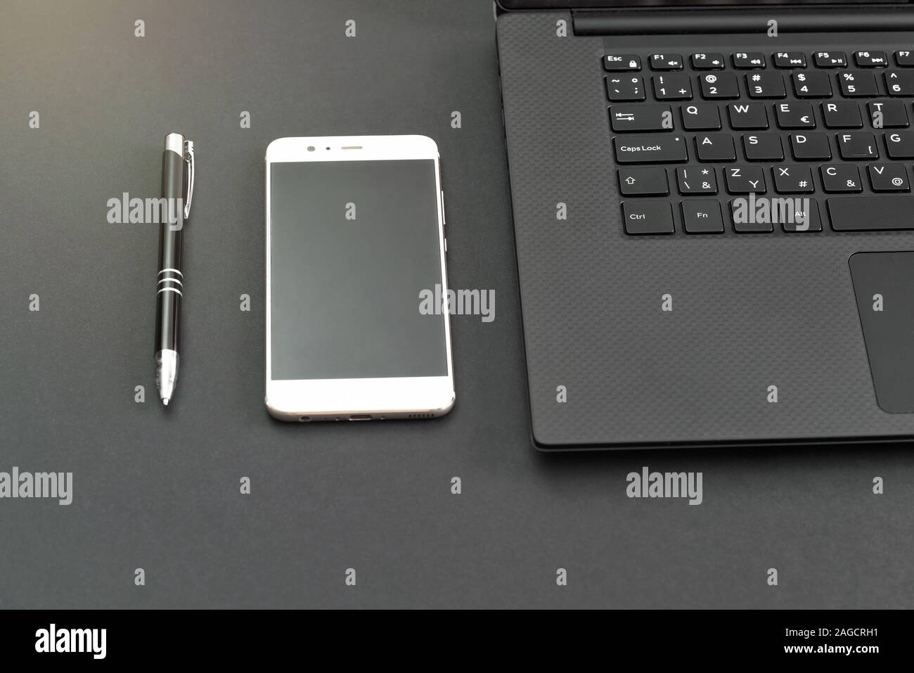 Stylo, smartphone et ordinateur portable sur le tableau gris, vue d'en haut Banque D'Images