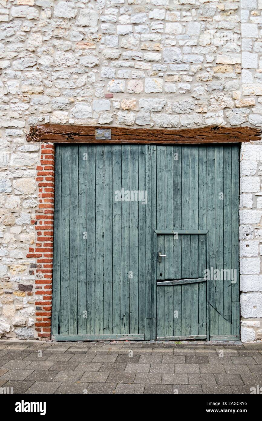 À guillotine double vert vieille porte de grange en bois avec linteau et mur en pierre de carrière, dans le centre du village historique d'Alt Breinig. Breinig-Stolberg (Rheinlan Banque D'Images