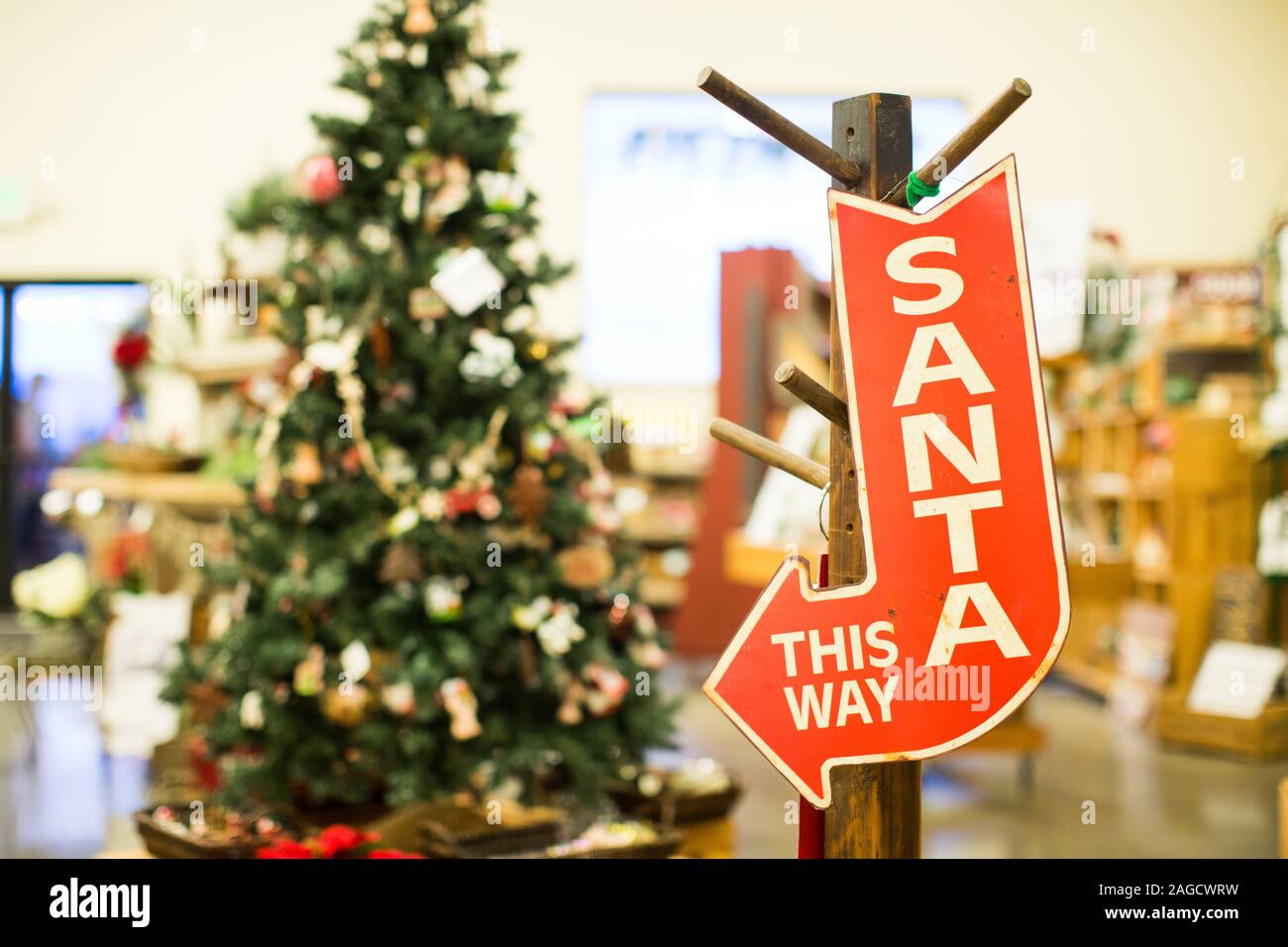 Une flèche rouge Santa de cette façon avec la signalisation décorée Arbre de Noël en arrière-plan Banque D'Images