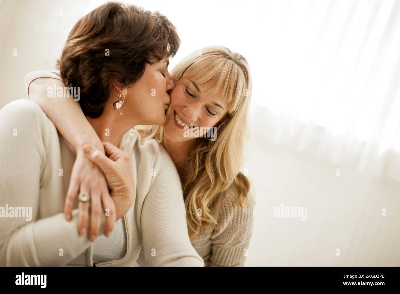 Jeune femme d'être embrassé sur la joue de sa mère. Banque D'Images