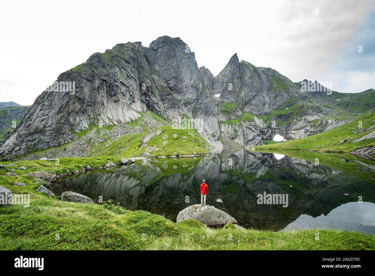 Homme debout à côté d'un lac dans les montagnes Lofoten une journée brumeuse Banque D'Images