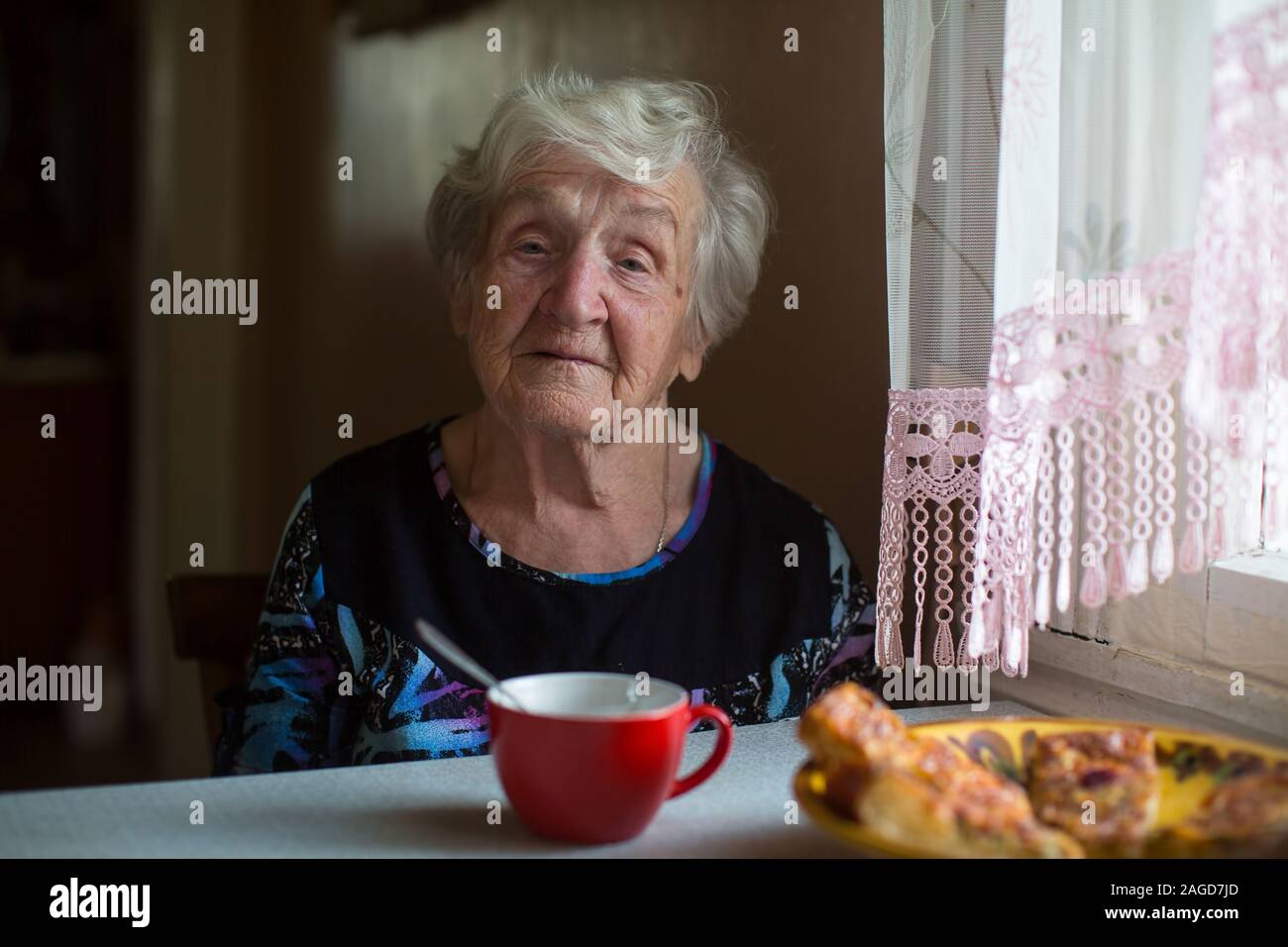 Portrait d'une vieille femme a petit déjeuner assis à la maison. Banque D'Images