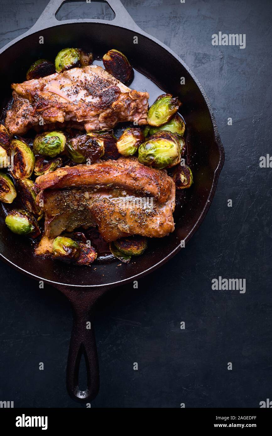 Prise de vue verticale grand angle de steak et de légumes grillés dans un pot noir sur une table noire Banque D'Images