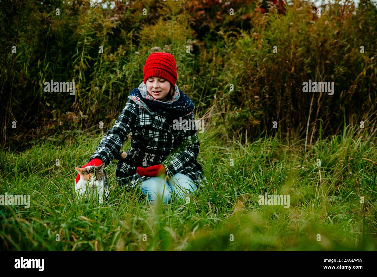 Une adolescente de flatter son chat dans un champ dans le Michigan Banque D'Images
