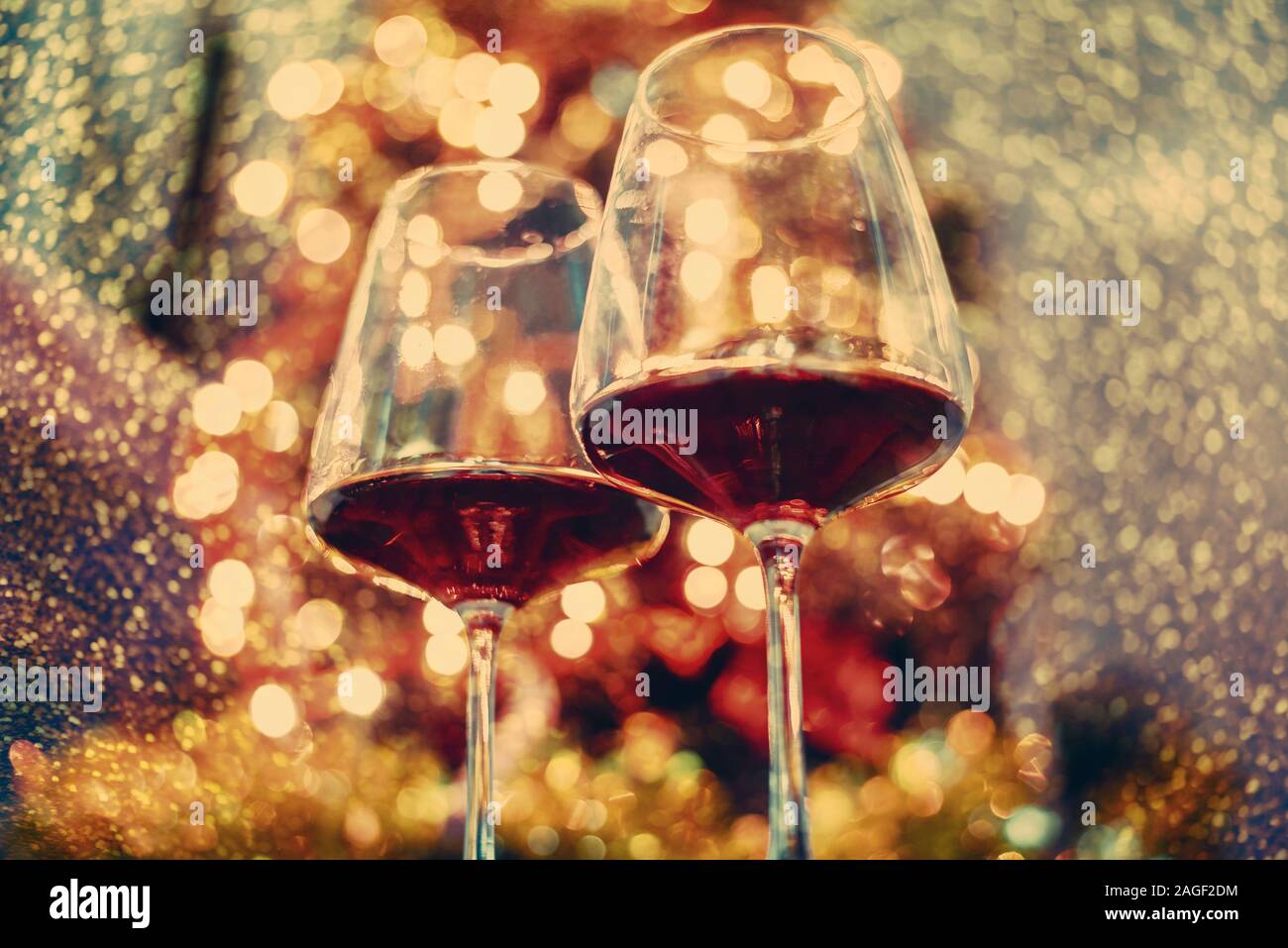 2 verre de vin rouge en face de bokeh les lumières d'arbre de Noël. Nouvel an et célébration de Noël partie. Maison de vacances romantique de luxe le dîner. Banque D'Images