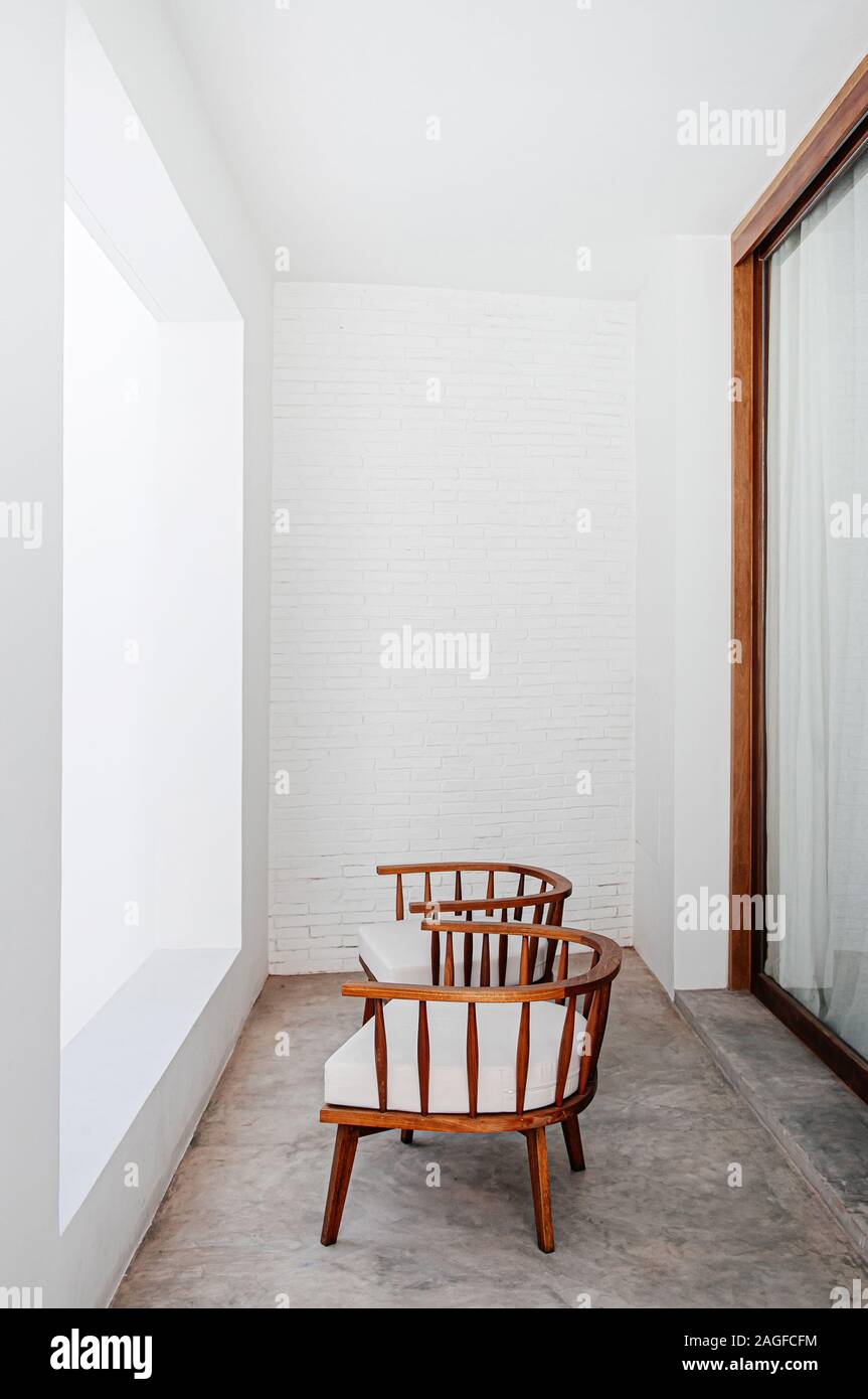 Chaises en bois contemporain au balcon avec mur de brique en béton blanc et fenêtre du sol au plafond. Style de décoration intérieure moderne minime Banque D'Images