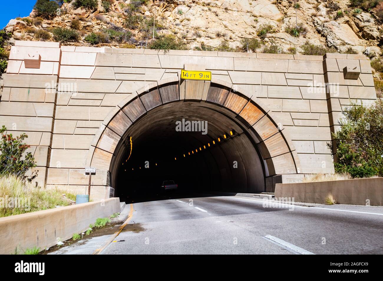 Tunnel creusé dans une montagne sur la Route 1, en Californie ; hauteur maximale affichée à l'entrée de l'autoroute, l'inclinaison à gauche en raison de la courbe de la route Banque D'Images