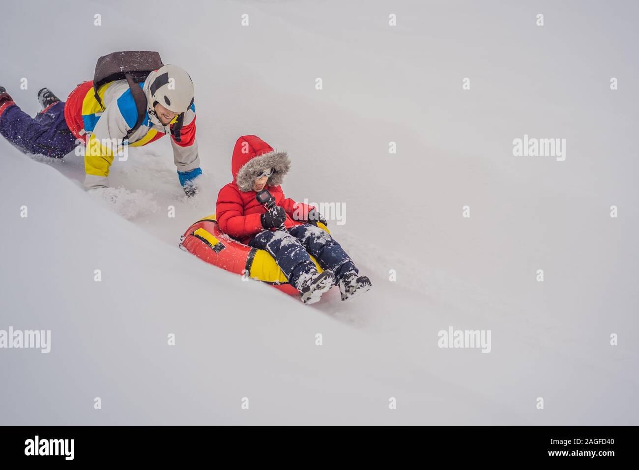 Père et fils s'amuser sur le tube de l'hiver. Plaisir d'hiver pour toute la famille Banque D'Images