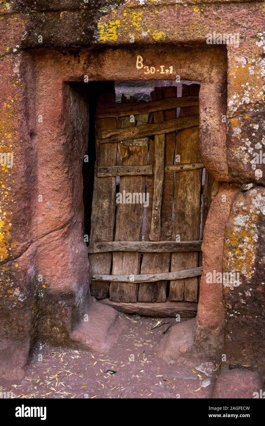 L'Éthiopie, région d'Amhara, Lalibela Arbatu Ensessa, Biblia, église Chirkos, porte de bois à l'état solide mur de pierre Banque D'Images