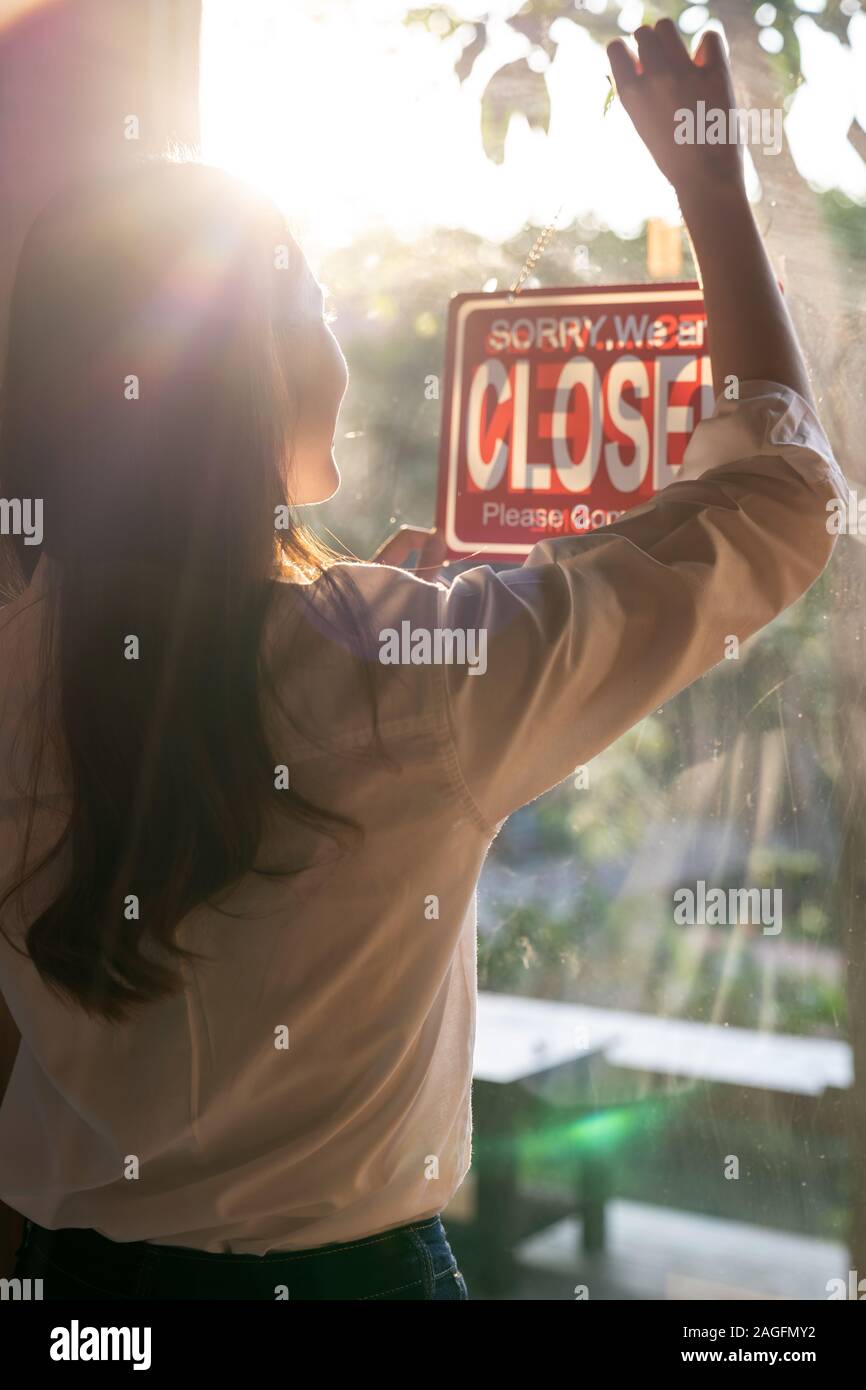 Vue arrière du jeune adulte femme propriétaire ouvrir son café café avec café ouvert à la fenêtre d'affichage Banque D'Images