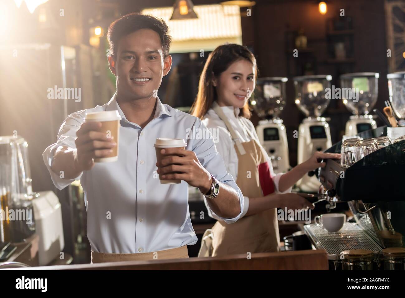 Portrait of asian barista de tenir la tasse de café à emporter et le service au client dans le café barista travaillant avec d'autres en arrière-plan Banque D'Images