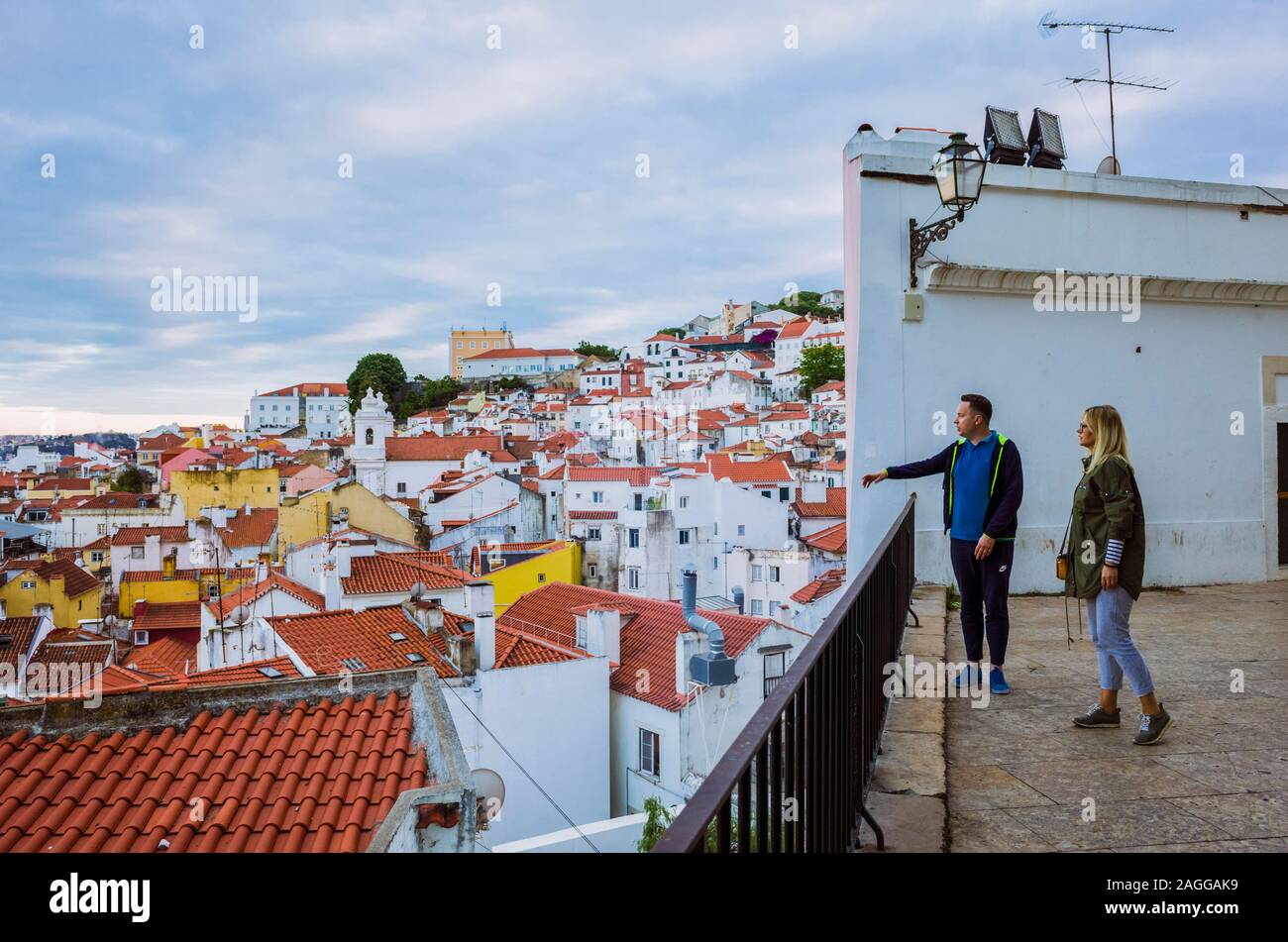 Lisbonne, Portugal : un couple regarde le coucher du soleil à l'Alfama vieille ville du Miradouro de Santo Estevao de vue. Banque D'Images