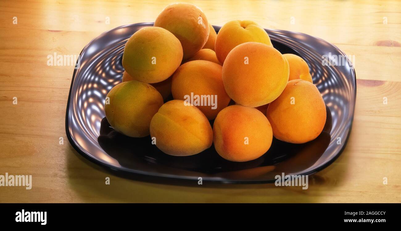 Les abricots sur un plat laqué noir sur la table Banque D'Images