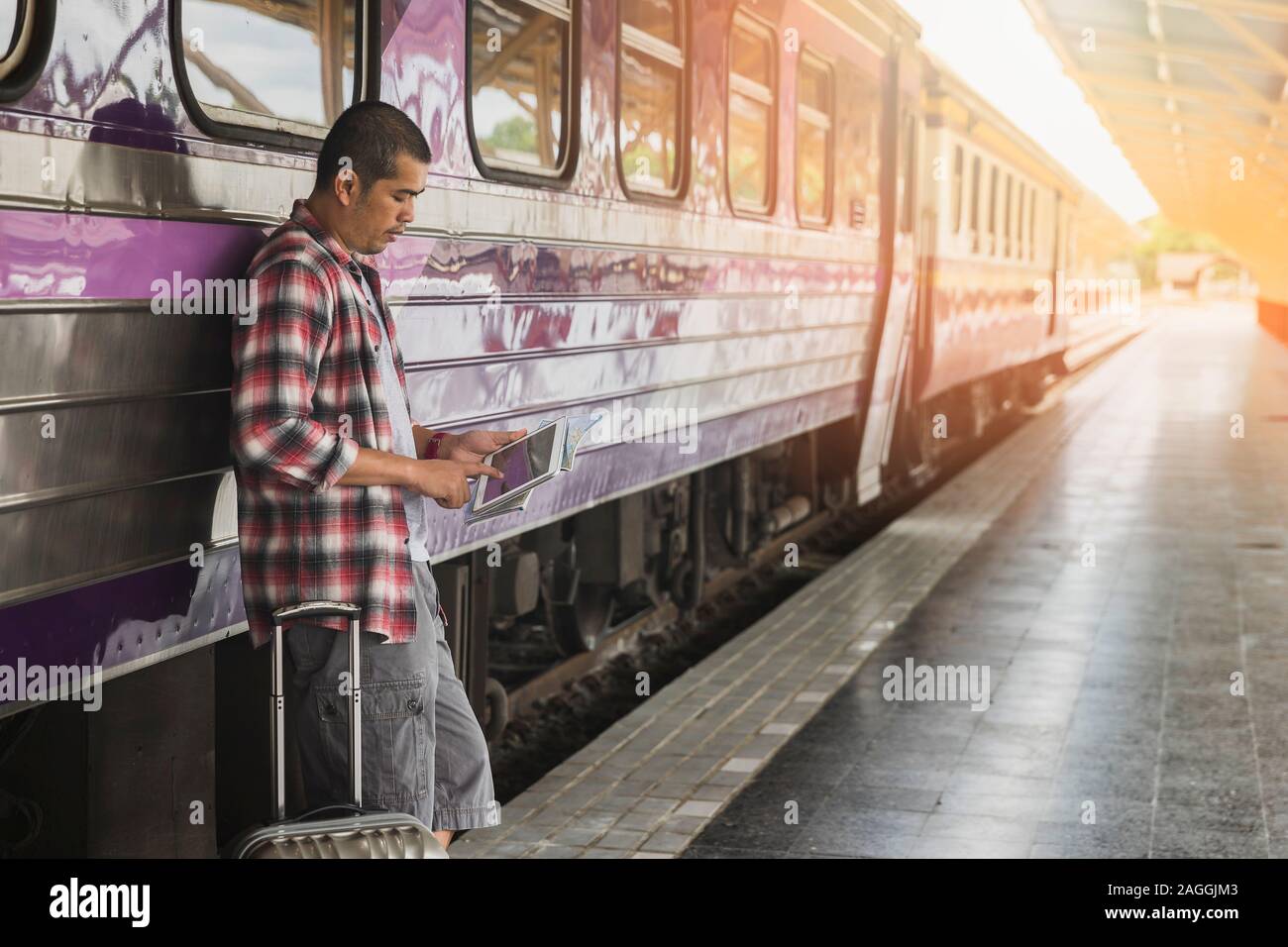 Voyageur avec bagages et tablette numérique en gare. Concept de voyage. Banque D'Images