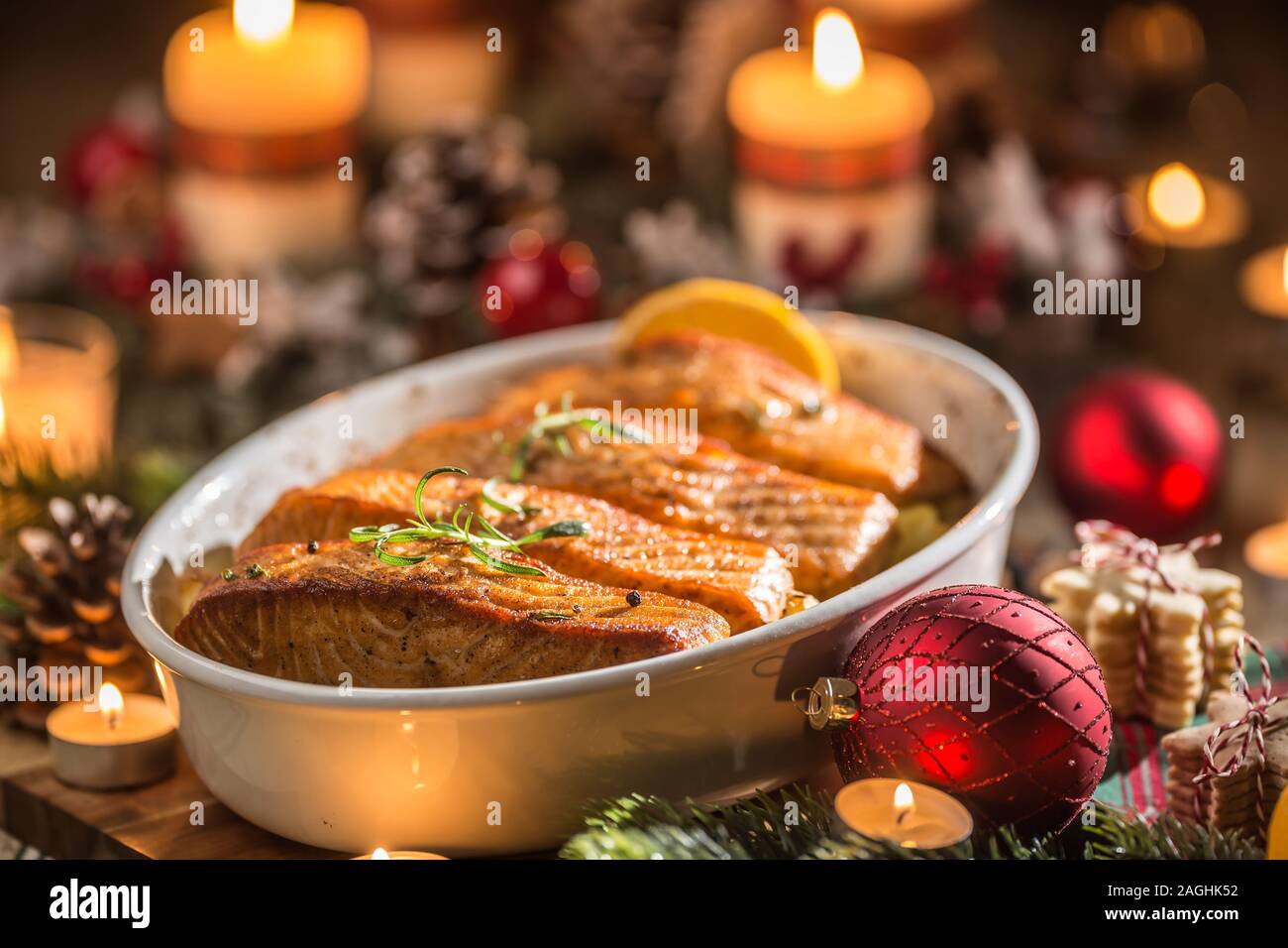 Repas de Noël de pêcher le saumon dans le plat à rôtir avec décoration de fête guirlande et des bougies. Banque D'Images