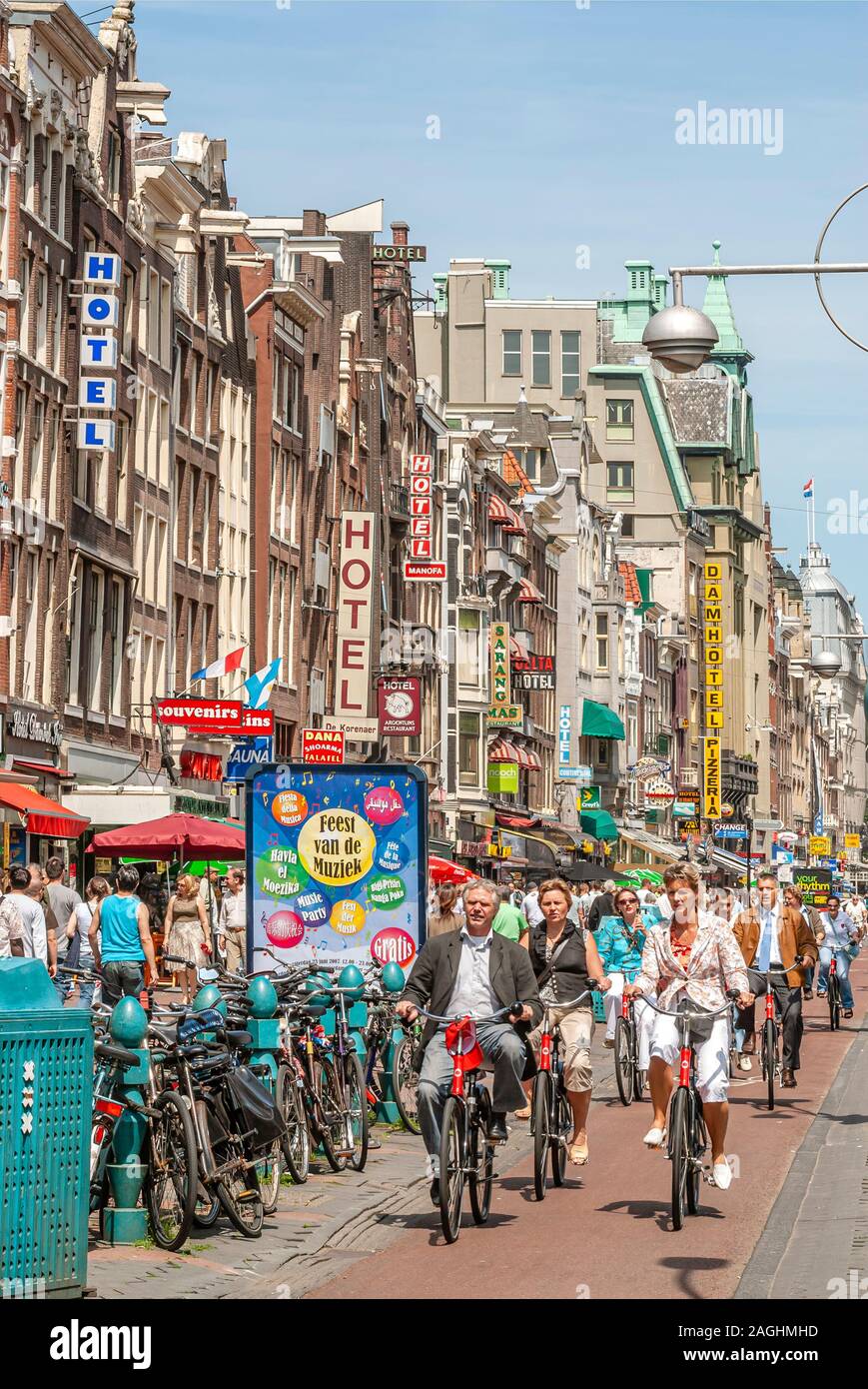 Cycliste au Damrak Rue commerçante dans le centre-ville d'Amsterdam Banque D'Images