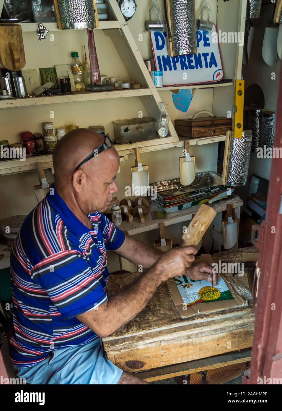 L'image spectaculaire d'un homme dominicaine travaillant dans son petit magasin alimentaire de métal avec un marteau et vives les ongles. Banque D'Images