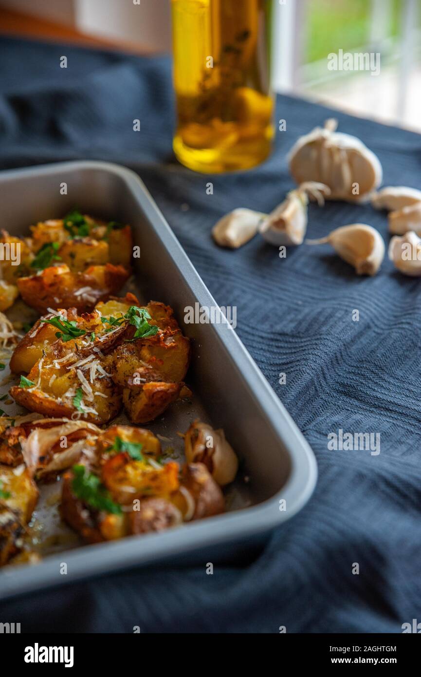 Des pommes de terre dans un plat à four avec l'ail frais et l'huile d'olive Banque D'Images