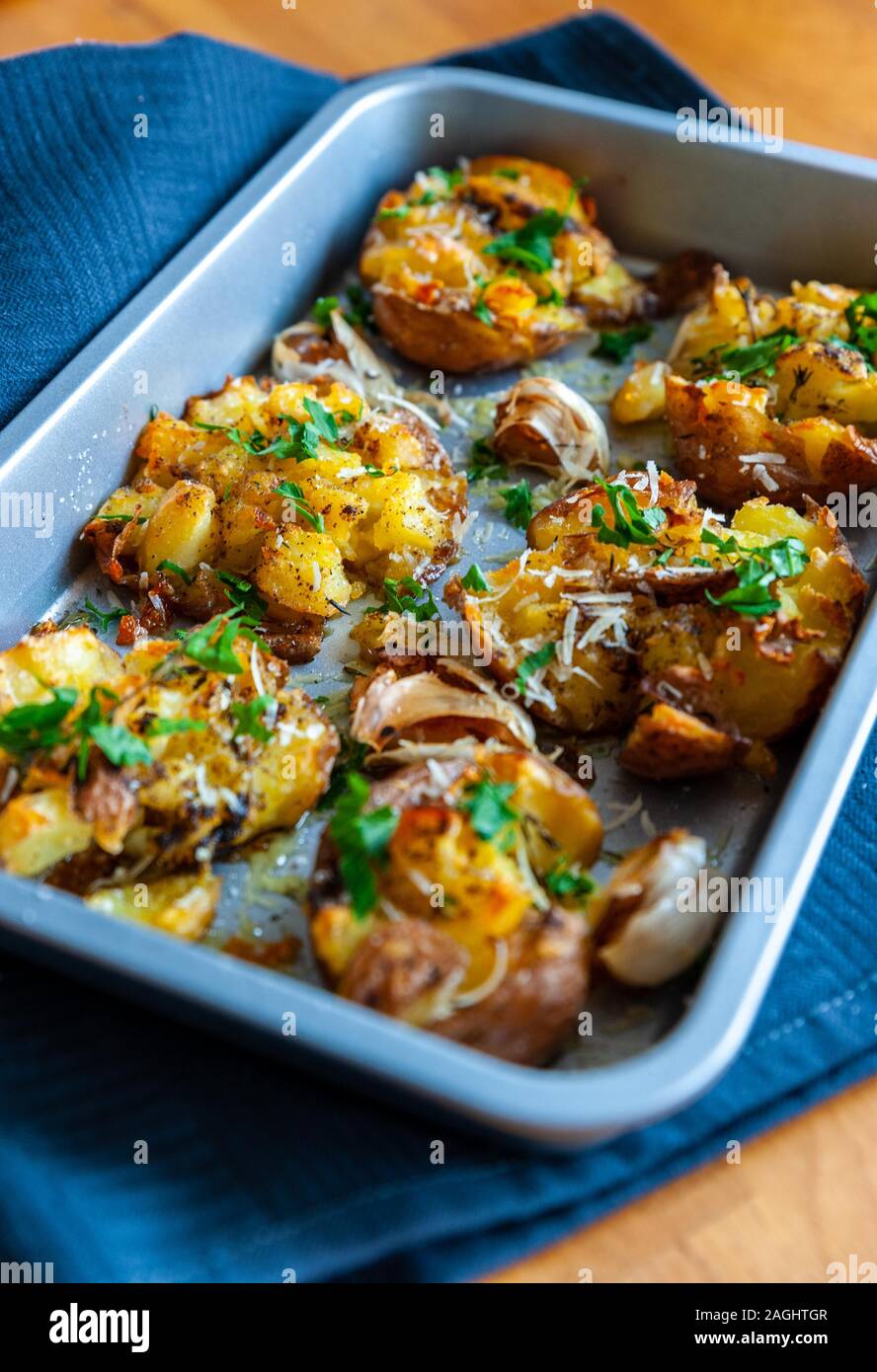 Pommes de terre rôties à l'aide de fines herbes et l'ail dans un plat à four sur une table en bois Banque D'Images