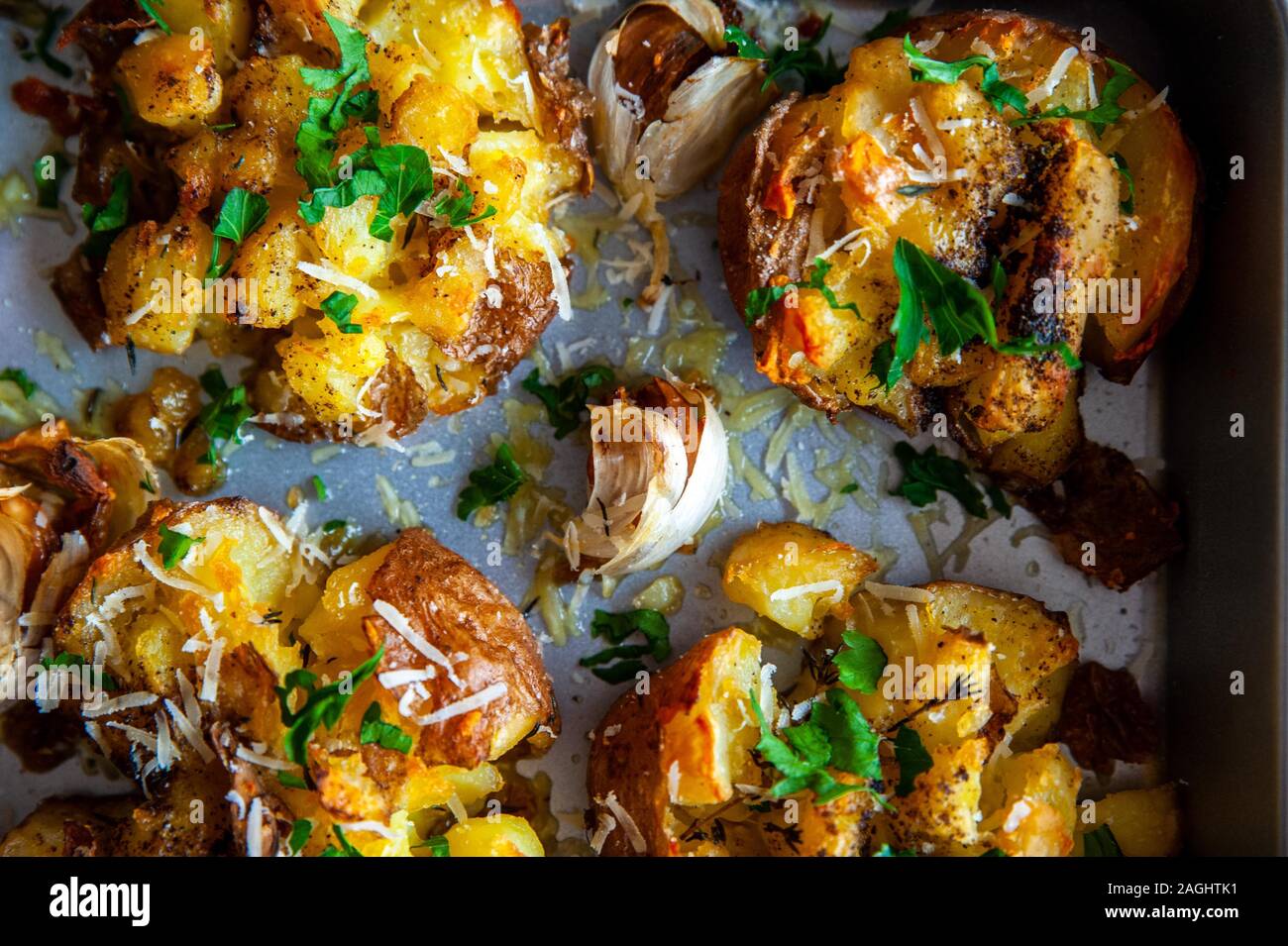 Gros plan de la pommes de terre rôties dans un plat à four avec de l'ail et fines herbes Banque D'Images