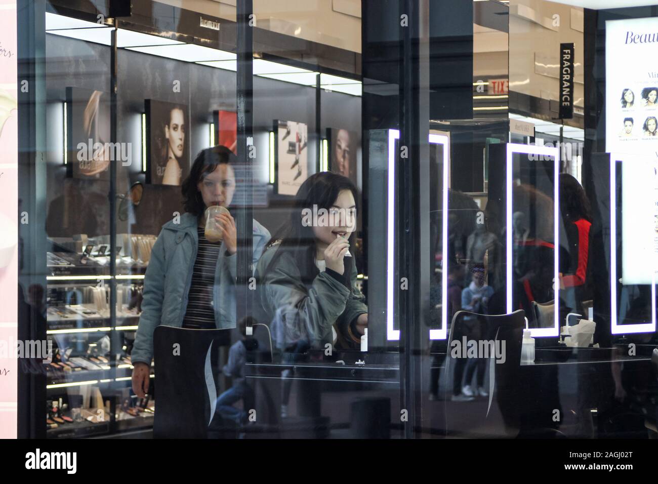 Les jeunes femmes ou adolescentes à beauty store vue à travers la fenêtre de la boutique Banque D'Images