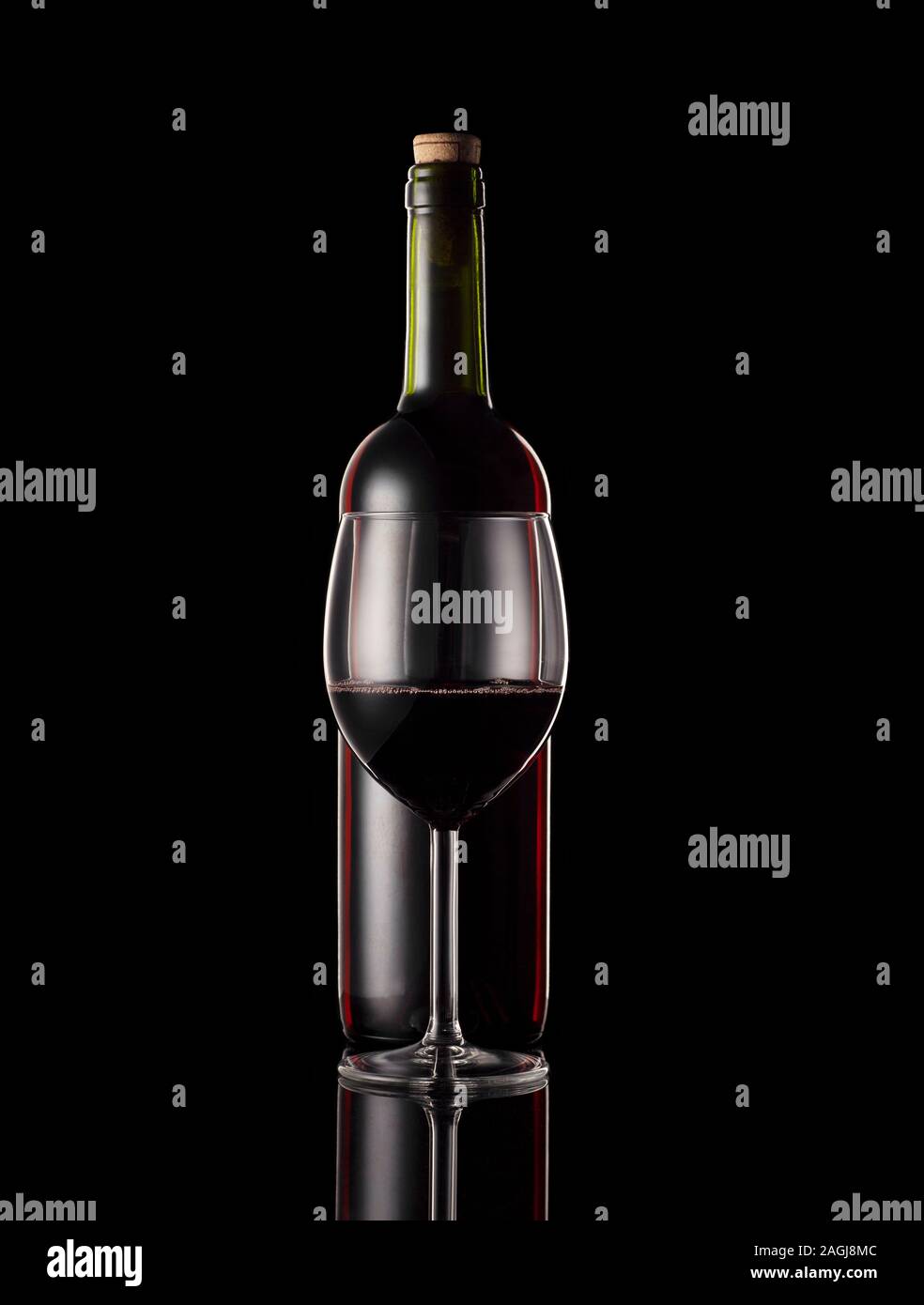 Bouteille de vin rouge et le verre avec fond noir et rim de l'éclairage. Banque D'Images