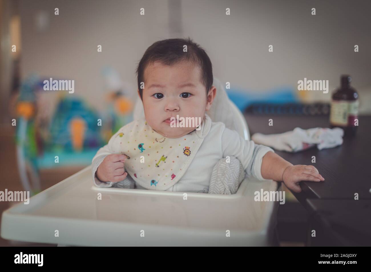 6 mois d'Asie baby boy sitting chaise haute à la maison Banque D'Images