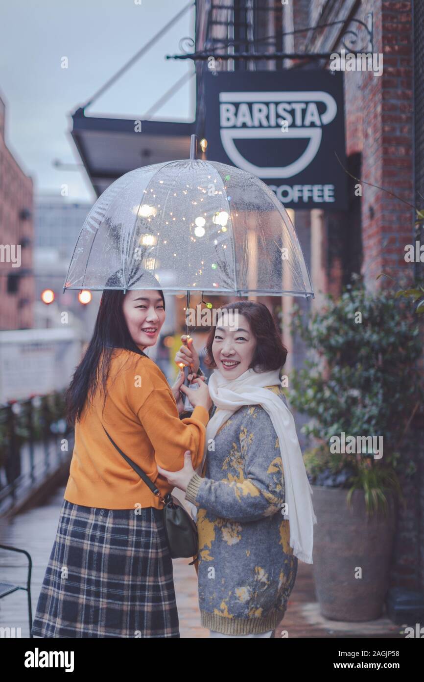 Portland, Oregon - Dec 15, 2019 : Happy asian mère âgée et sa fille adulte porte parapluie à Portland Pearl District Banque D'Images