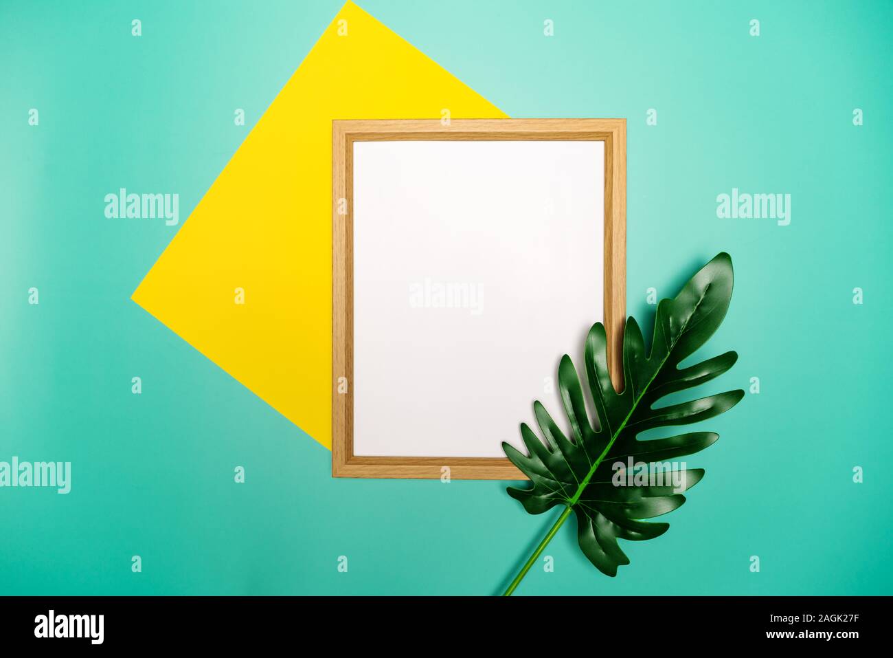 La composition de l'été. Feuilles de palmiers tropicaux, sur papier jaune, le cadre photo Blanc sur fond vert pastel. Banque D'Images