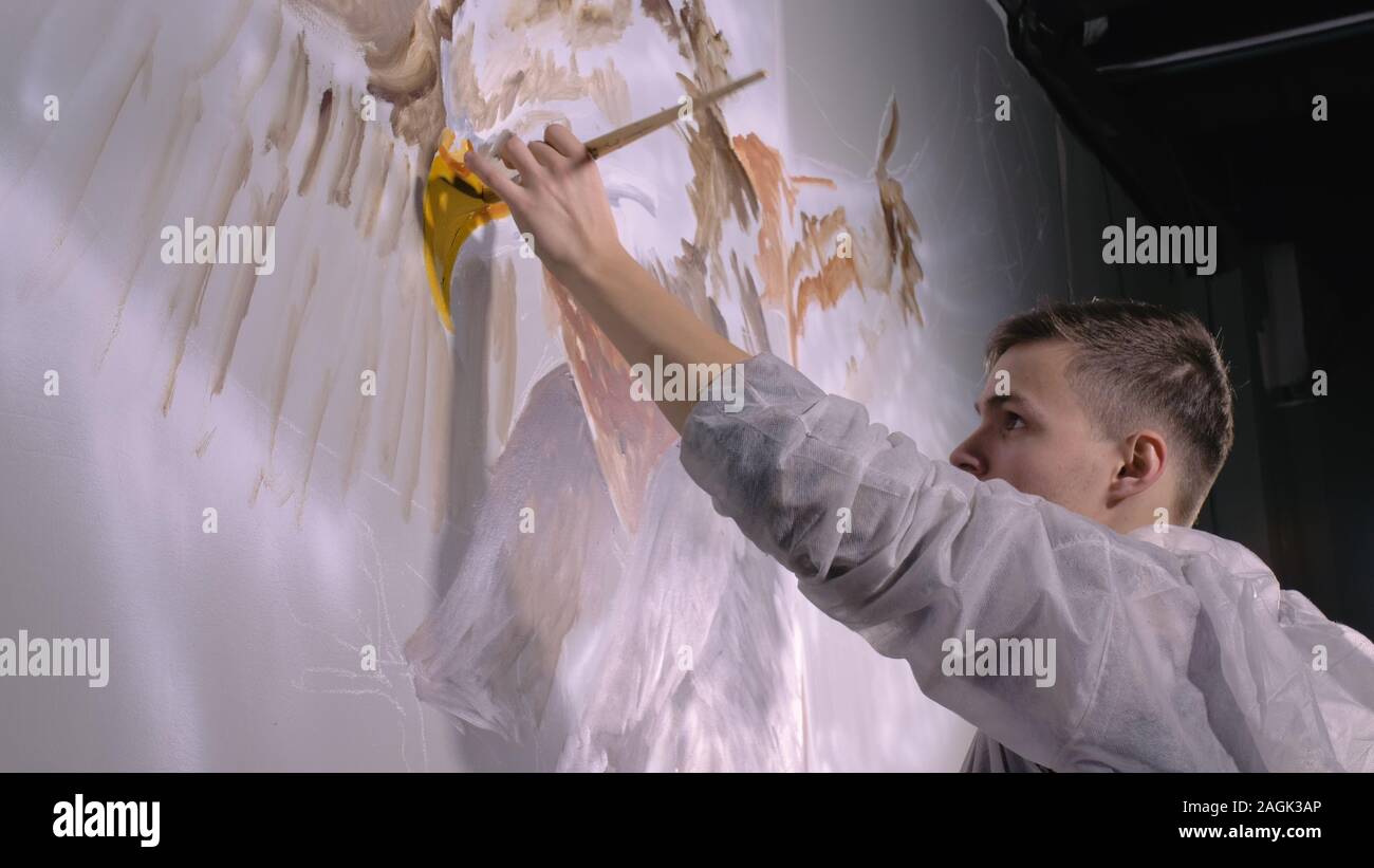 Concepteur de l'artiste dessine un aigle sur le mur. Décorateur artisan photo peintures à l'acrylique couleur d'huile. Peintre peintre vêtu de couche de peinture. À l'intérieur. Banque D'Images
