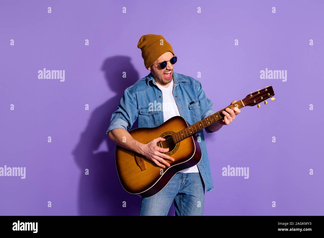 Photo de cheerful attractive grossier bel homme wearing cap holding guitar with hands playing instrument musicien portant des lunettes plus isolés Banque D'Images