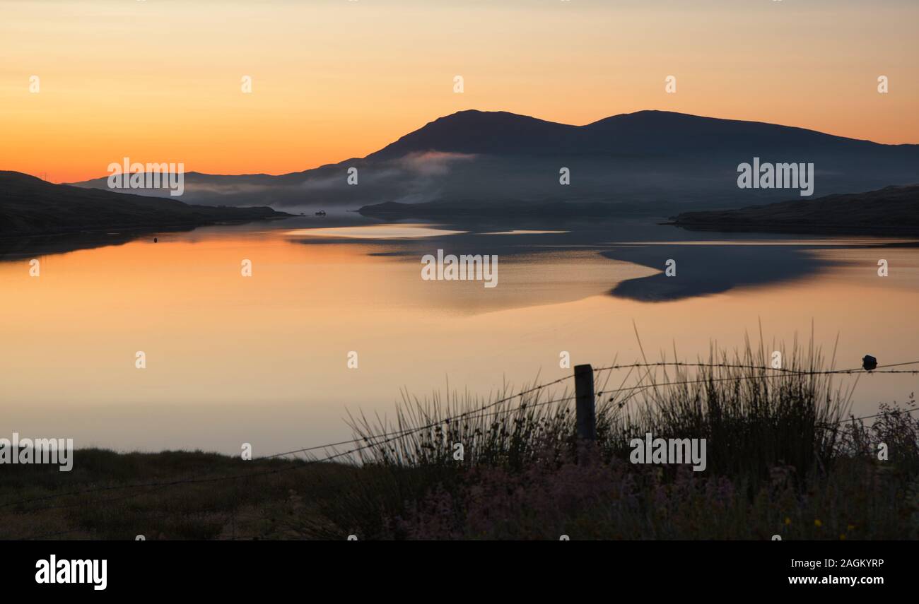 Le lever de soleil orange se reflète dans le loch, l'île de Lewis, les Hébrides extérieures, en Écosse Banque D'Images