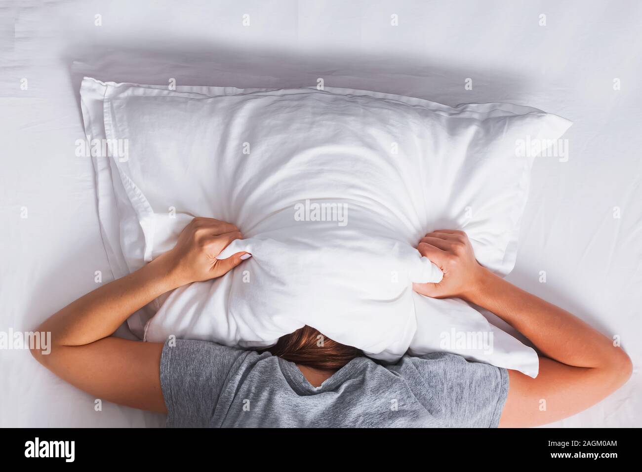 Femme couchée sur le lit et qui couvre sa tête avec l'oreiller Photo Stock  - Alamy