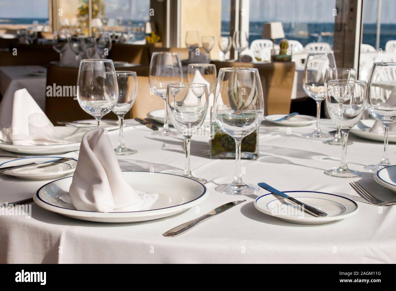 Vaisselle de table dans un restaurant près de la mer. Les verres,  assiettes, couverts et serviettes de table sur une nappe Photo Stock - Alamy
