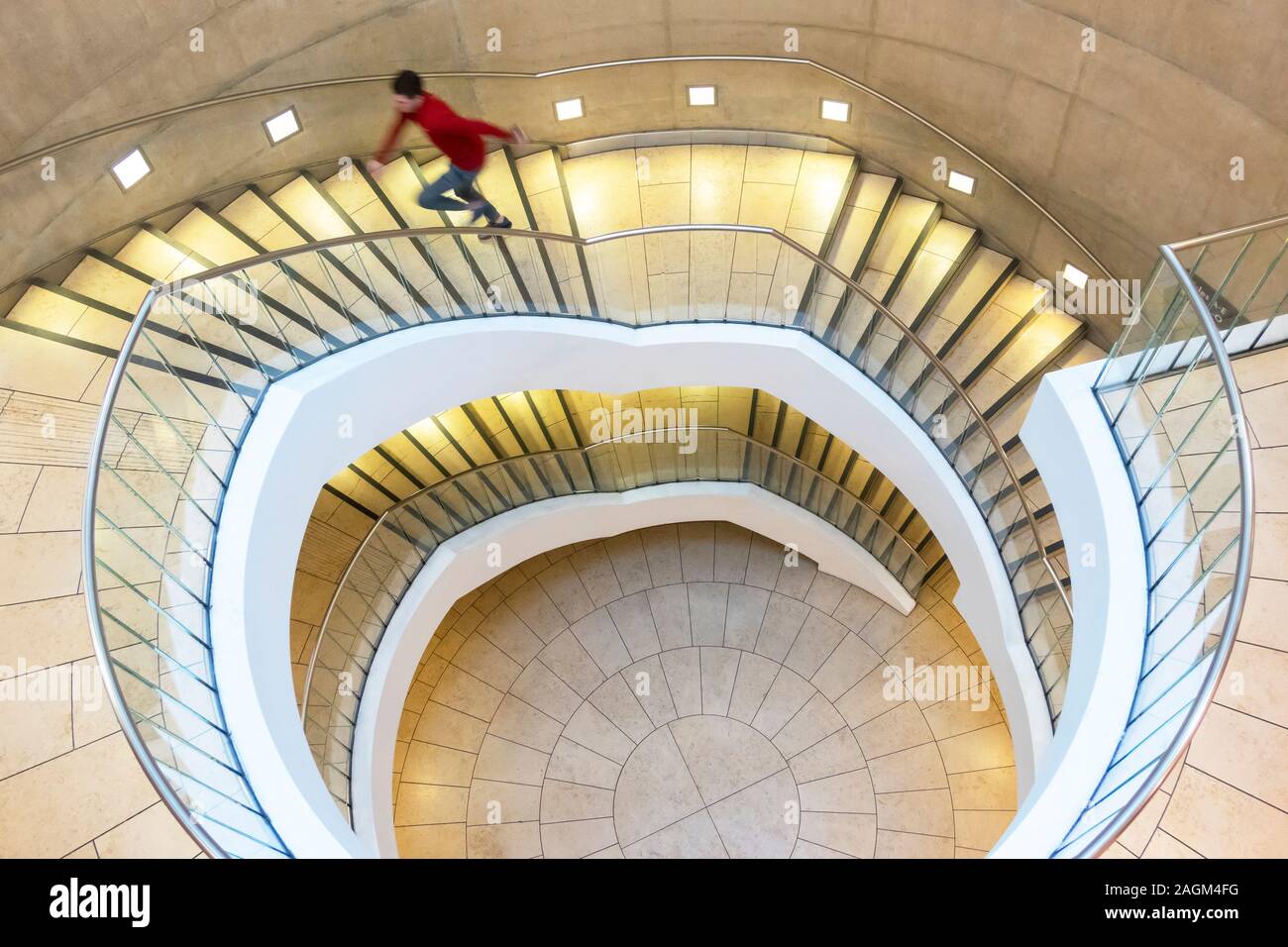 Un jeune homme dans un pull-over rouge courant un Escalier en colimaçon dans un garage dans le centre commercial Liverpool One Banque D'Images