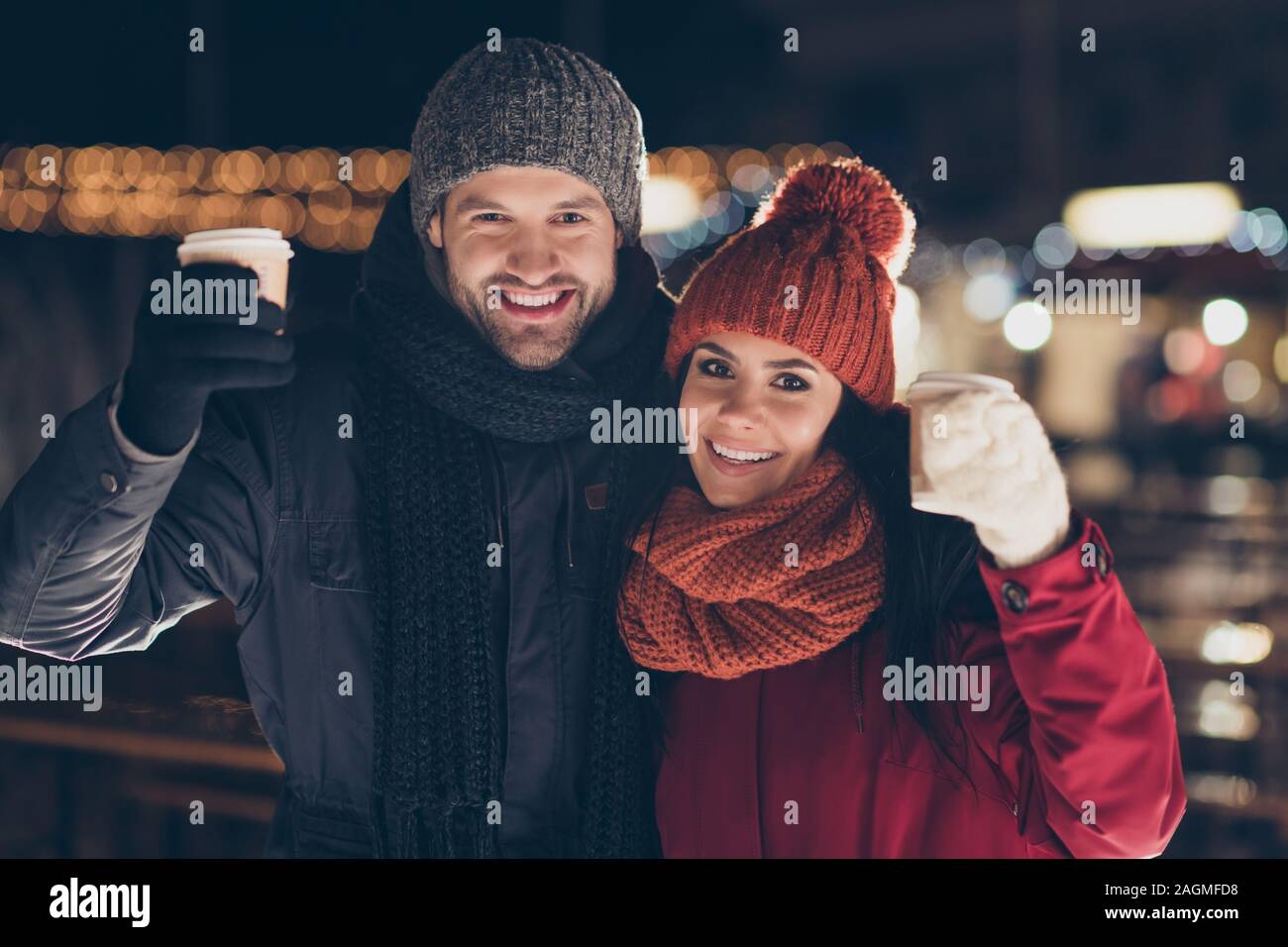 Joyeux Noël. Photo de deux personnes paire avec boisson chaude dans les mains de célébrer la soirée x-mas toasts dit tasses portant manteaux chauds à l'extérieur Banque D'Images