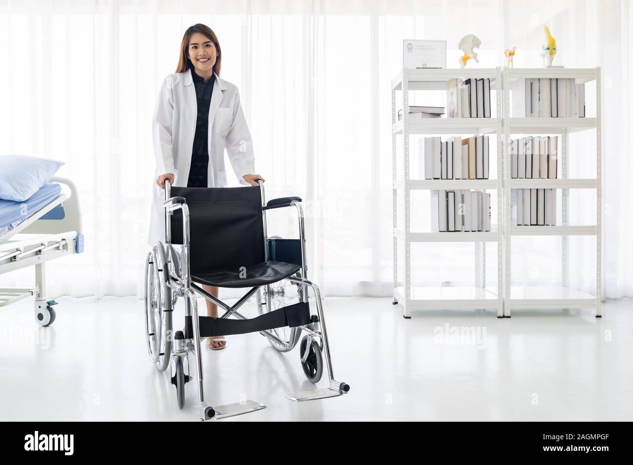 Portrait of female doctor holding medical fauteuil roulant professionnel dans la salle d'examen clinique de l'hôpital Banque D'Images
