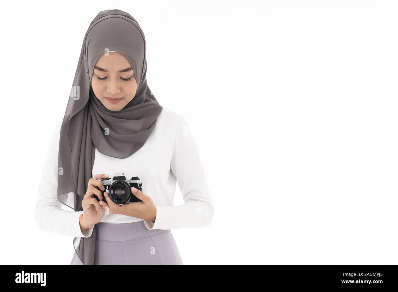 Portrait of happy young adult asian muslim woman holding a camera et photographe et souriant. Studio shot of woman isolated on white zone Banque D'Images