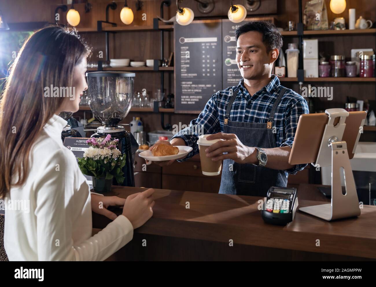 Portrait of asian barista de tenir à emporter, café et croissant tasse et de servir au client en café barista travaillant avec d'autres en arrière-plan Banque D'Images