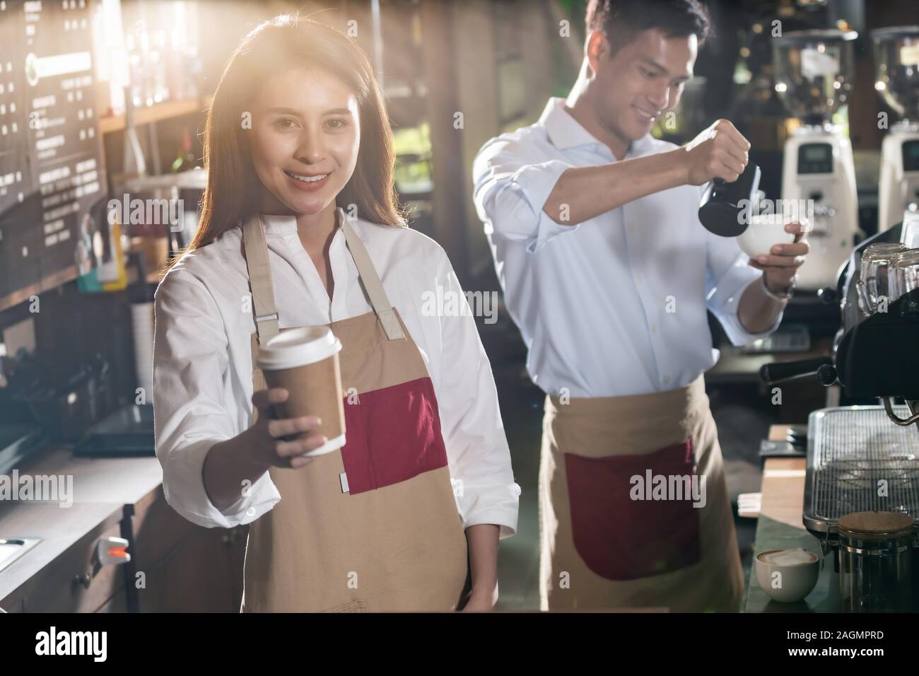 Portrait of asian barista de tenir la tasse de café à emporter et le service au client dans le café barista travaillant avec d'autres en arrière-plan Banque D'Images