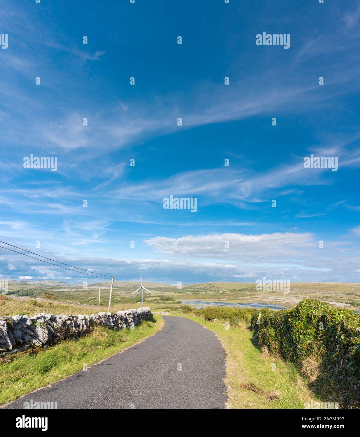 Route de campagne dans le Burren, Comté de Clare, Irlande avec la dépression de Carran, une énorme doline ou dépression karstique avec un turlough (lac éphémère) Banque D'Images