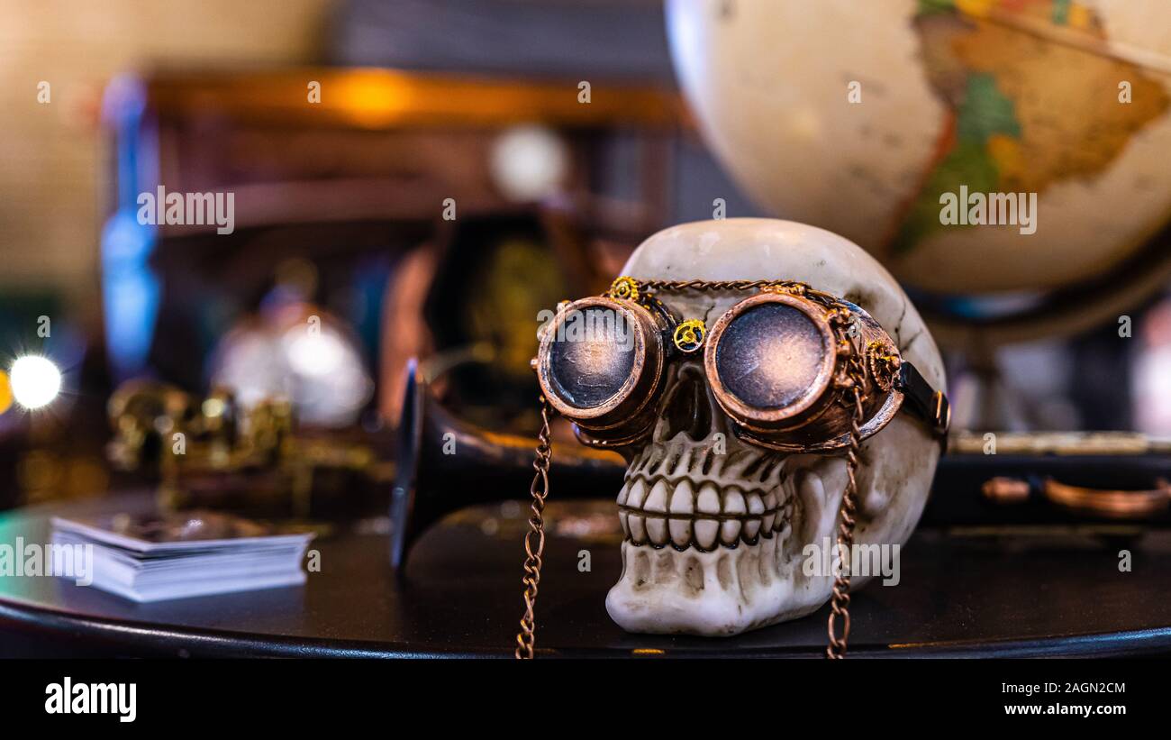 Riga, Lettonie - 12 Avril 2019 : tête de squelette avec un arrière-plan sur lunettes steampunk avec globe et vieille voiture - image Banque D'Images