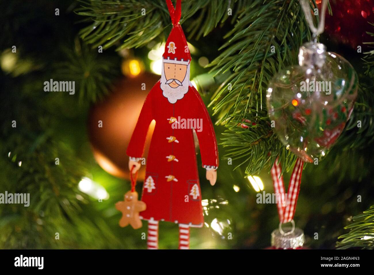 Une décoration de Noël en bois de Père suspendue dans un arbre de Noël artificiel Banque D'Images