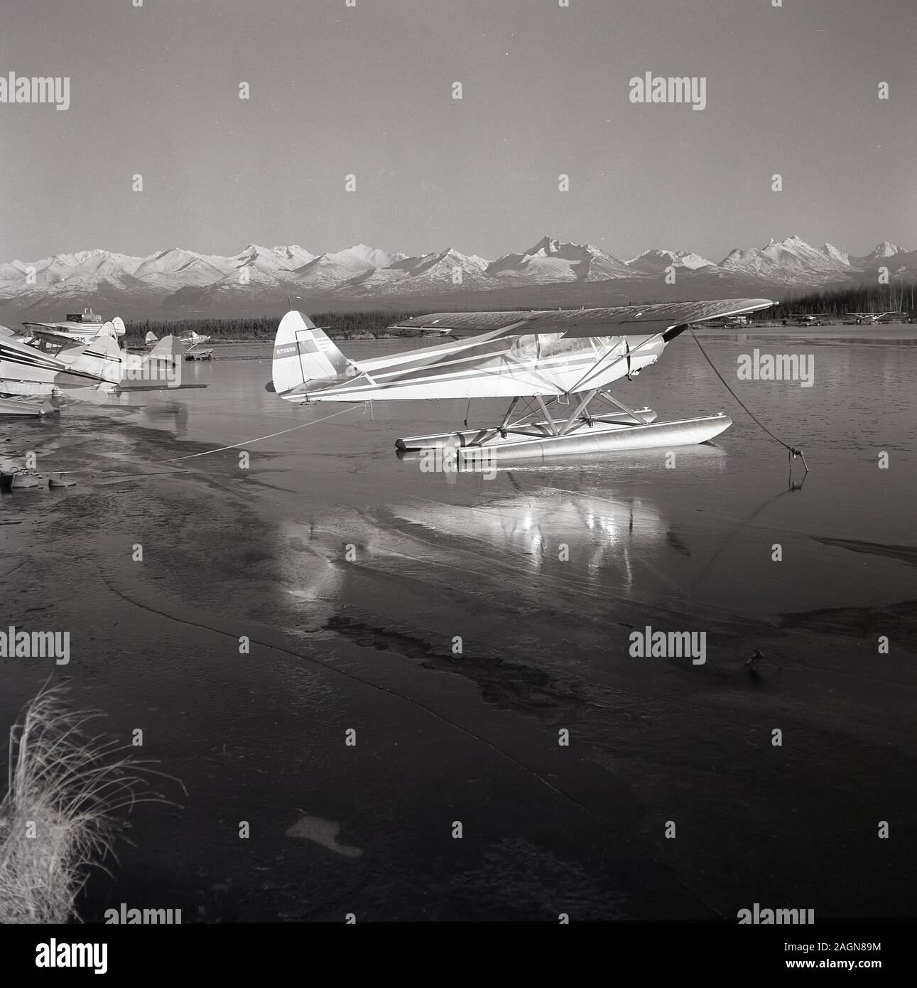 Années 1960, historiques, les hydravions assis sur un lac près de l'aéroport d'Anchorage, Anchorage, Alaska, USA, avec la Chugach Mountains en arrière-plan. Banque D'Images