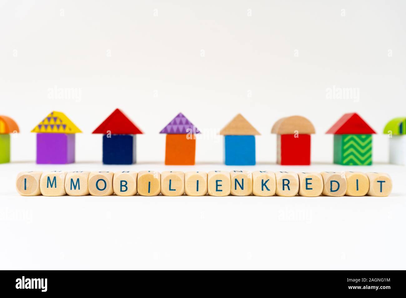 Bloc en bois avec des lettres pour dire 'Immobilienkredit' (Allemand pour prêt immobilier) en face de maisons jouet coloré Banque D'Images