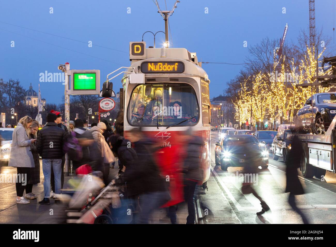 Tramway de Vienne ; les personnes traversant la route Universitatsring en face d'un tramway s'arrêtaient à un arrêt de tramway la nuit, centre-ville de Vienne, Vienne Autriche Europe Banque D'Images